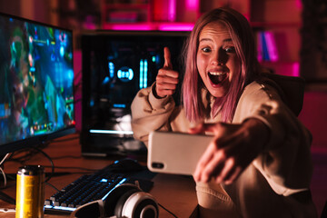 Wall Mural - Image of girl taking selfie on cellphone while playing video game