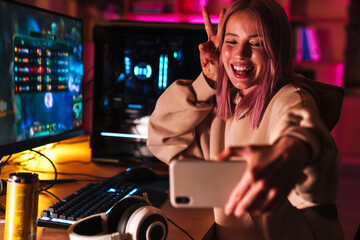 Poster - Image of girl taking selfie on cellphone while playing video game