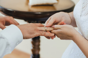 Wall Mural - bride puts a gold wedding ring on the finger of the groom