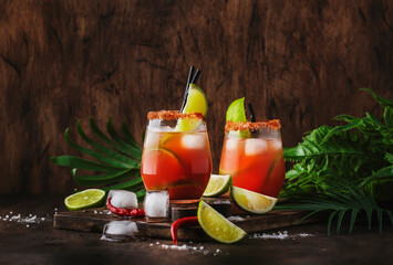Fototapeta michelada - mexican inspired bloody mary alcoholic cocktail with beer, lime juice, tomato juice, spicy sauce and spices, copy space