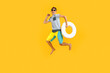 happy excited teenager in sunglasses, having fun and jumping, holding an inflatable ring on a yellow background
