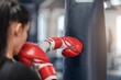 Female boxer in gloves hitting big punching ball during self defence class at gym, empty space