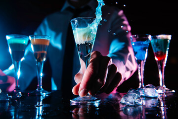 Barman preparing cocktail shots at the bar counter. Barman mixing drinks at the night club.