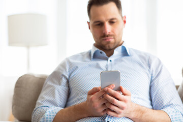 Bored adult man using smart phone at home