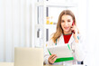 © Masato - Female beautiful wearing a doctor uniform holding a green paper chart and talking on mobile phone.