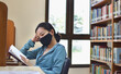 © sawaddee3002 - Woman with protective mask reading a book in library