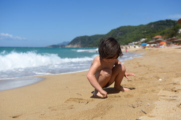 Wall Mural - Child playing in sand on the beach. Cheerful boy play on send on summer holiday