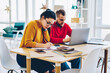 © BullRun - Young male and female sitting  at desktop making research on netbook and writing information, serious woman in eyewear making accountings of bills and  receipts for family budget man banking