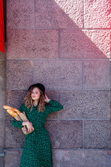 Portrait woman dressed in French style with baguette in hand. French style of Paris. Close-up of French woman in stylish clothes holding fresh baguettes and smiling. Place for an inscription or logo