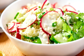 Sticker - Fresh summer vegetable salad of couscous, radish, cucumbers, parsley and lemon. Vegan food. Spring or summer food. Salad with couscous and raw vegetables close-up.