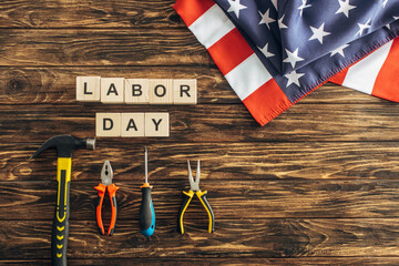 Poster - top view of american flag near instruments and cubes with labor day lettering on wooden surface