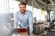 © Westend61 - Portrait of smiling young businessman with laptop in a factory
