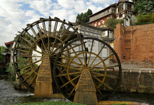 Old Wood Water Wheels Turn On A Rushing Creek In The Ancient Naxi Town Of Lijiang (Dayan), Yunnan Province, China.