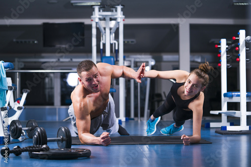 Sporty couple in gym. Attractive sports couple are working out together in gym. Fitness man and woman giving each other a high five after the training session in gym.