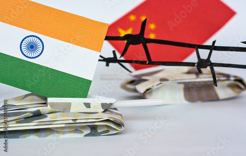 Photo Chinese and Indian flags on tanks between barbed wire, grunge style photo