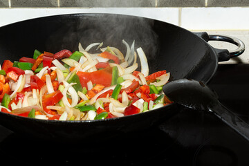 Wall Mural - Cocinando cebolla y pimientos en un wok.