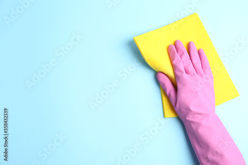 Cuadros en Lienzo Person in rubber glove with rag on light blue background, closeup of hand