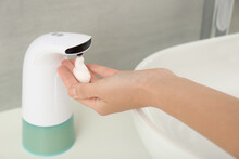 Woman Using Automatic Soap Dispenser In Bathroom, Closeup