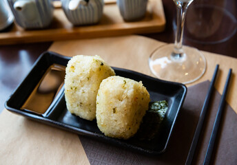 Fresh Japanese triangular onigiri with rice at black plate