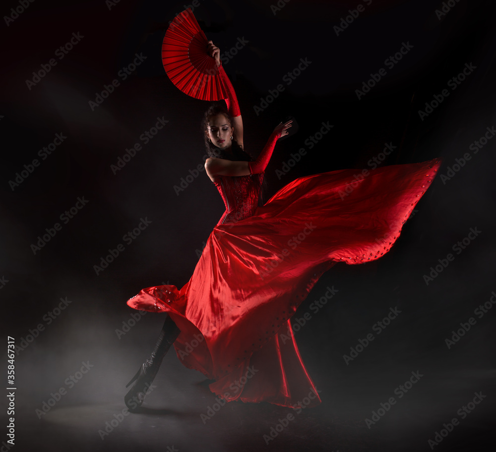 Flamenco woman spanish dancer in red dres performs with fan in dance at black background, studio shot - obrazy, fototapety, plakaty 