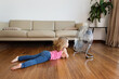 © Lisa Tichané - Little girl lying by electric fan on hardwood floor at home