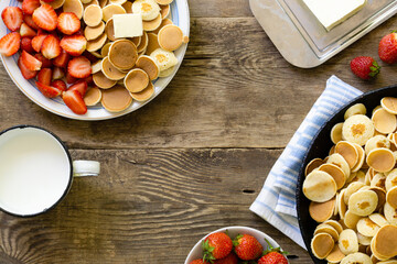 Wall Mural - Breakfast with trendy tiny pancakes and strawberry on a wooden background