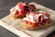 Two Toasts With Fresh Tomatoes And Cured Ham. Delicious Appetiser Italian Prosciutto And Spanish Iberian Ham Snack