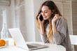 © Drobot Dean - Portrait of joyful woman talking on cellphone while working with laptop