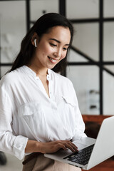 Wall Mural - Attractive young brunette asian woman using laptop