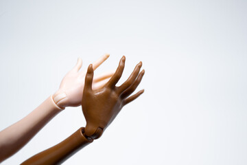 Doll hands on a white background: one brown, the second white. Space for text
