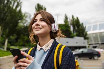 Poster - Student girl walking outdoors in headphones