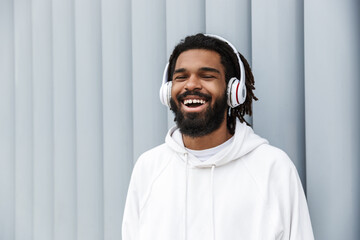 Wall Mural - Cheery young man walking outdoors while listening music