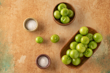 fresh ripe green plums on a table served with salt