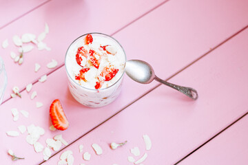 Wall Mural - layered summer dessert with strawberries, sponge cake and yogurt on a pink tree background.