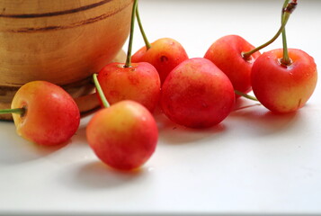 Juicy, sweet variety of yellow cherries on a white background close-up, next to a wooden mortar, still life