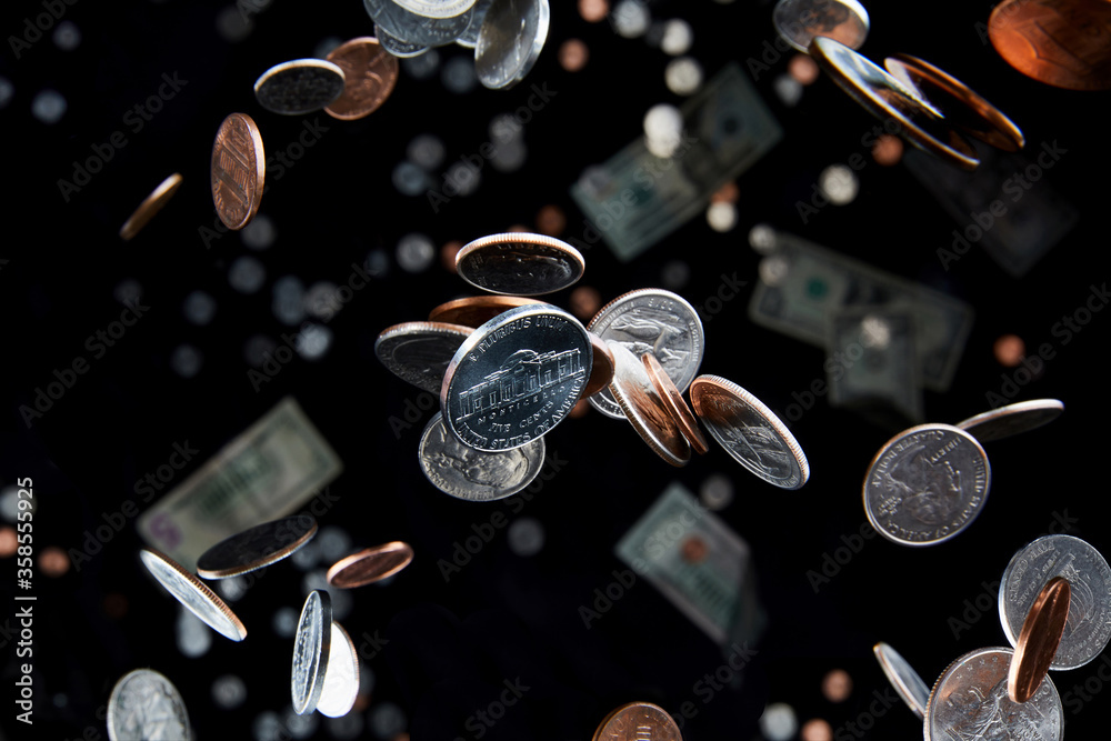 Falling coins flying through the air represent economy and finance with a zero-gravity nickel as focus of currency.