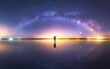 © Juan Lopez/ADDICTIVE STOCK - Silhouette of anonymous man standing on reflection surface of water and reaching out to starry colorful night sky with milky way
