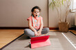 © Manuel Ruiz Alba/ADDICTIVE STOCK - Surprised little girl sitting on mat near window at home resting after practicing yoga throughout video tutorials on tablet