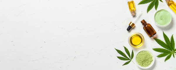 Wall Mural - Cannabis oil and green leaves at white table.