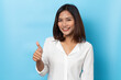© suriya - Happy asian young woman smiling against made finger thumbs up OK gesture on blue background