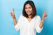© suriya - asian young woman with fingers crossing isolated on blue background