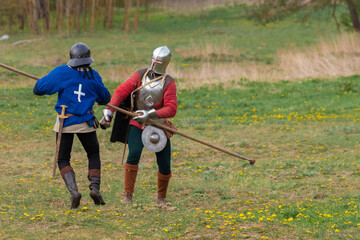 Knights in armor fight on the battlefield. Reconstruction of an ancient battle of the 15th century.