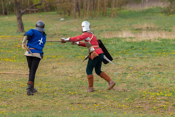 Knights in armor fight on the battlefield. Reconstruction of an ancient battle of the 15th century.