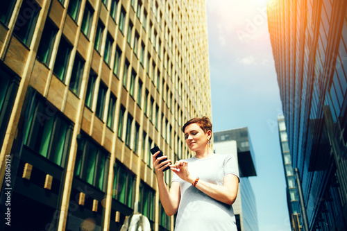 Fotomural A woman looks at her phone on the street of the city, remote work concept
