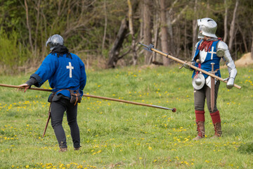 Knights in armor fight on the battlefield. Reconstruction of an ancient battle of the 15th century.