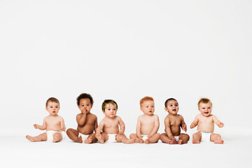 row of six multi ethnic babies smiling in studio