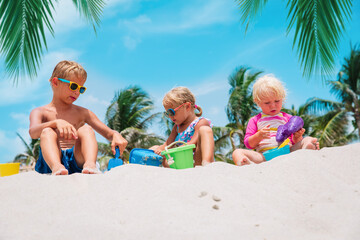 Wall Mural - kids play with sand on beach, boy and girls on tropical vacation