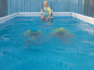 Cute boys in bathing suit swim and play in frame  swimming pool for country house. Children are happy together. Sunny summer day. concept of family vacations and active lifestyle after quarantine