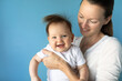 © kieferpix - In studio portrait of mother and her smiling baby girl on blue background