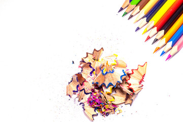 Multi-colored, bright sharpened pencils in different positions on a white background. Pencil sharpener. Pencil shavings.